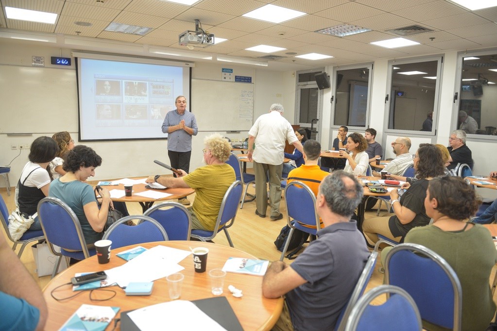 כיתה עם סטודנטים ומרצה, מצגת מוקרנת על המסך.
